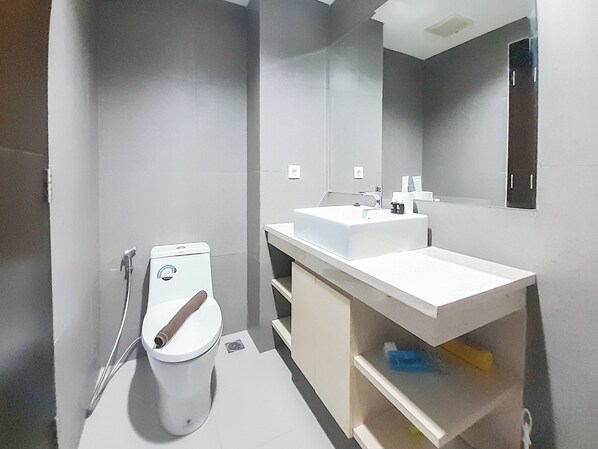A modern bathroom with a toilet, bidet, sink, and mirror.