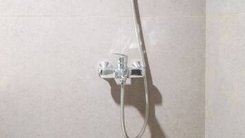 A shower with a flexible hose and a control unit mounted on a tiled wall.