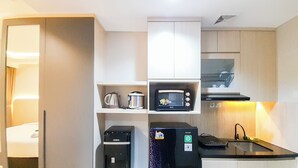 Una kitchenette compacta equipada con microondas, cafetera y refrigerador.