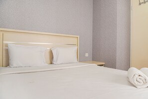 Cozy retreat with a neatly made bed, geometric-patterned wall, and a bedside table with a lamp.