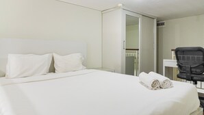 A hotel room with a large bed, a desk, and a chair. - Good Deal Studio Loft At Nifarro Park Apartment (Jakarta)