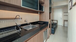 Cozinha moderna com bancada preta, pia de aço inoxidável e armários de madeira.