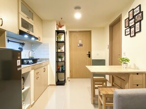 Enjoy casual dining at this kitchen with a refrigerator, stainless steel range hood, and wooden dining table.