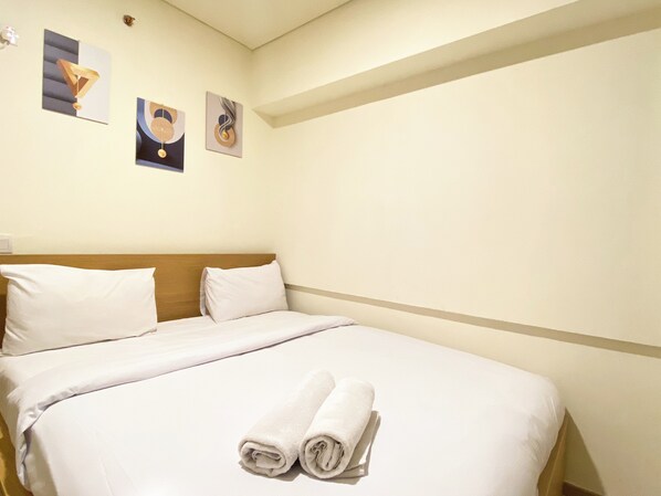 Relax in a serene space with a neatly made bed, featuring crisp linens and plush towels.