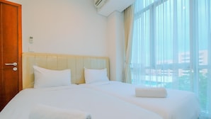 A hotel room with two beds, a wooden door, and a large window with curtains. - Good Choice And Elegant 2Br Apartment Capitol Park Residence (Jakarta)