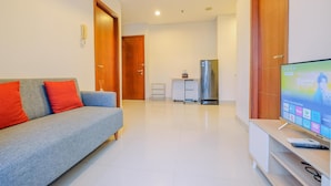 A modern living room with a grey sofa, red cushions, a flat-screen TV, and a wooden cabinet. - Good Choice And Elegant 2Br Apartment Capitol Park Residence (Jakarta)