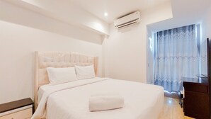 Una cama bien hecha con una toalla blanca, una mesita de noche y una mesita auxiliar.