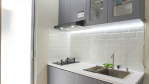 A modern kitchen with grey cabinets, a white countertop, and a stainless steel sink. - Strategic And Warm Studio At Bassura City Apartment (Jakarta)