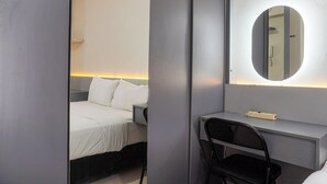 A hotel room with a bed, a desk, a chair, and a mirror. - Strategic And Warm Studio At Bassura City Apartment (Jakarta)