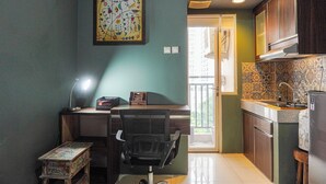 A compact kitchen with a dining area, a small table, and a chair. - Good Choice And Simply Studio Apartment Margonda Residence 4 (Depok)