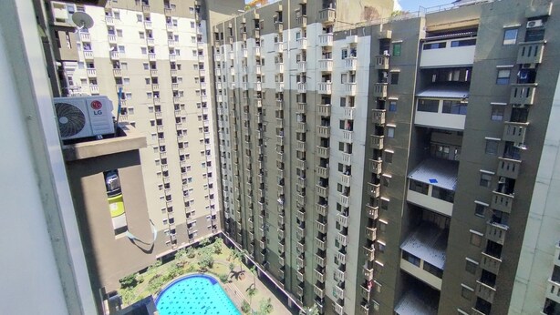 A high-rise residential building with multiple balconies, a swimming pool, and a satellite dish. - Best Deal And Comfy 1Br Apartment Gateway Ahmad Yani Cicadas (Bandung)