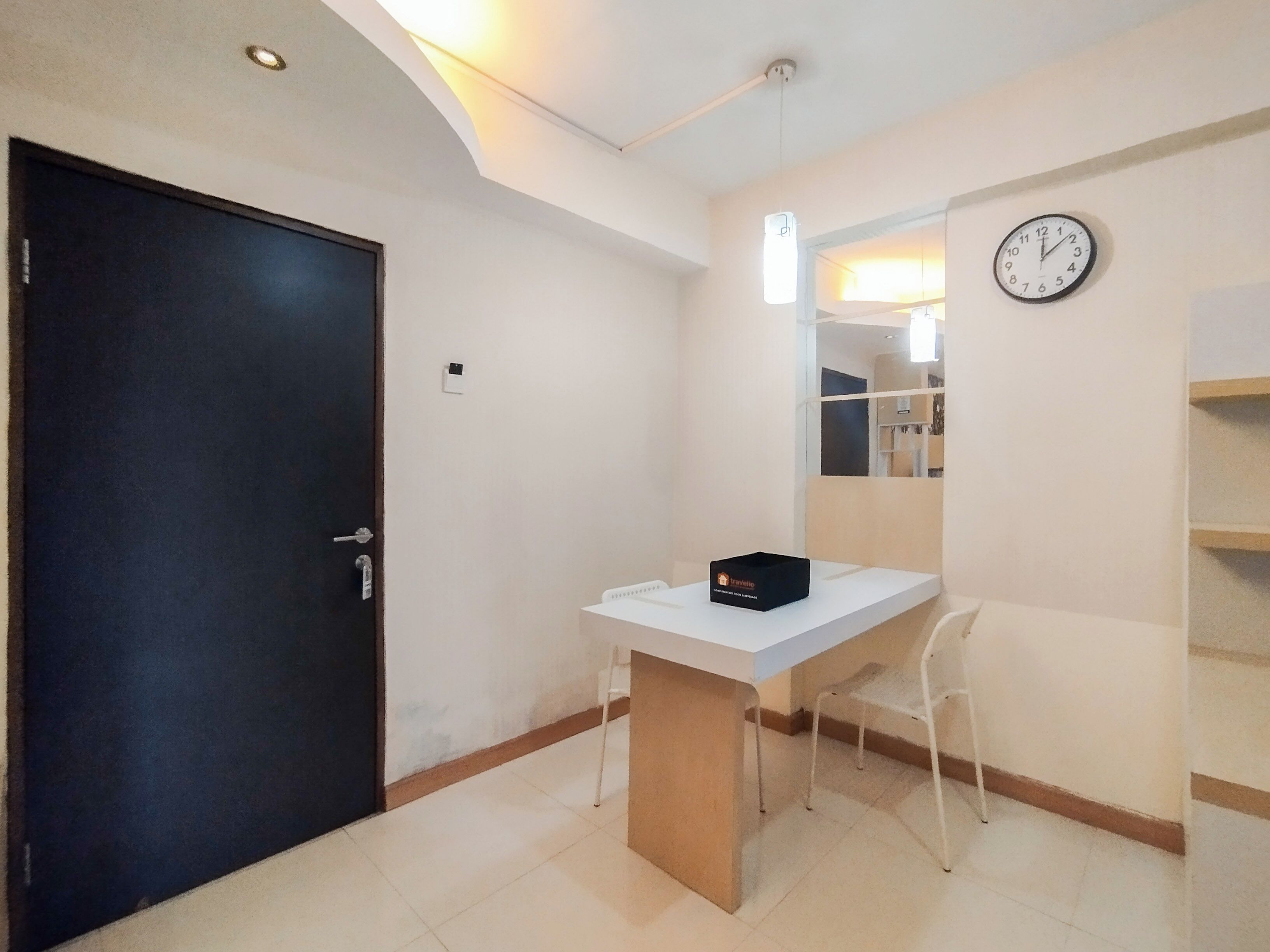 A small, well-lit room with a desk, chair, and a clock on the wall.