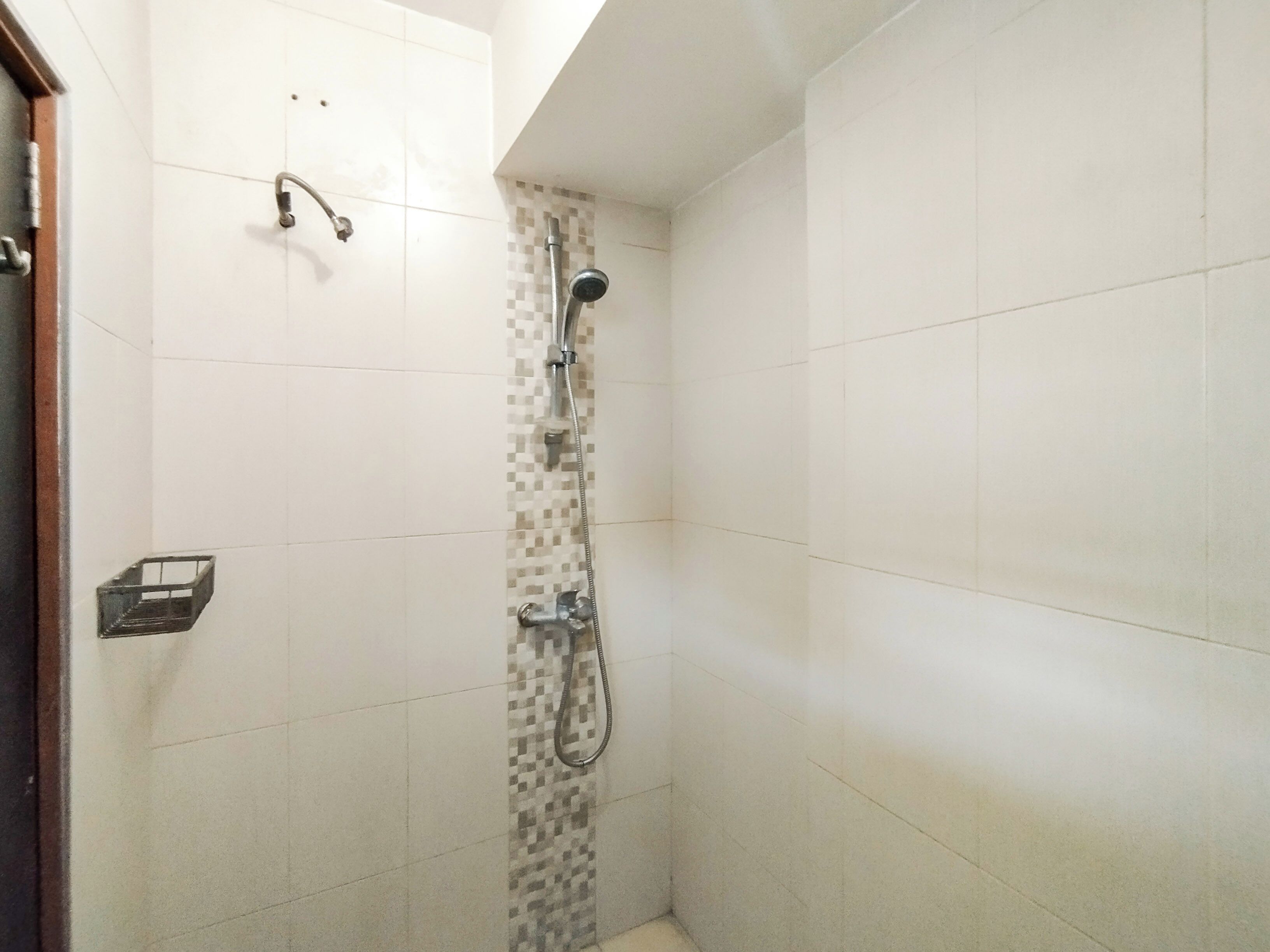 A small, tiled shower area with a showerhead and a handheld shower attachment.