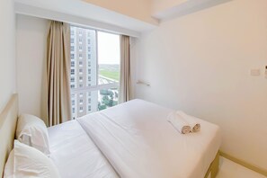 A hotel room with a large bed, a window with curtains, and a view of buildings outside.