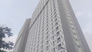A tall, modern high-rise building with a grid of windows and balconies. - Best Deal And Homey Studio At Gunung Putri Square Apartment (Gunung Putri)