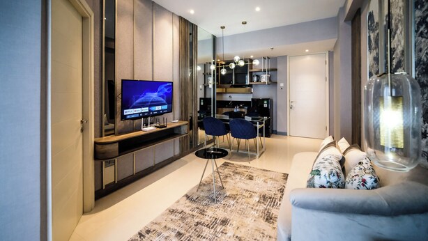 A modern living room with a flat-screen TV, a sofa, and a dining area with chairs.