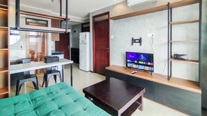 A compact living space with a kitchenette, a dining area, a TV, and a green sofa.