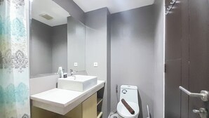 Un baño moderno con lavamanos, espejo y inodoro blancos.