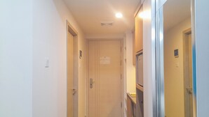 A narrow hallway with wooden flooring, white walls, and doors leading to rooms. - Tranquil And Modern Studio At Mataram City Apartment (Ngaglik)