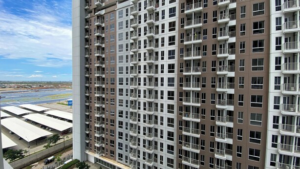 A high-rise building with multiple balconies and a view of a waterfront area. - Comfortable Design Studio At Tokyo Riverside Pik 2 Apartment (Teluknaga)