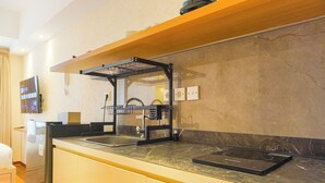 A modern kitchen with a marble countertop, a built-in dishwasher, and a black induction cooktop. - Comfortable Design Studio At Tokyo Riverside Pik 2 Apartment (Teluknaga)