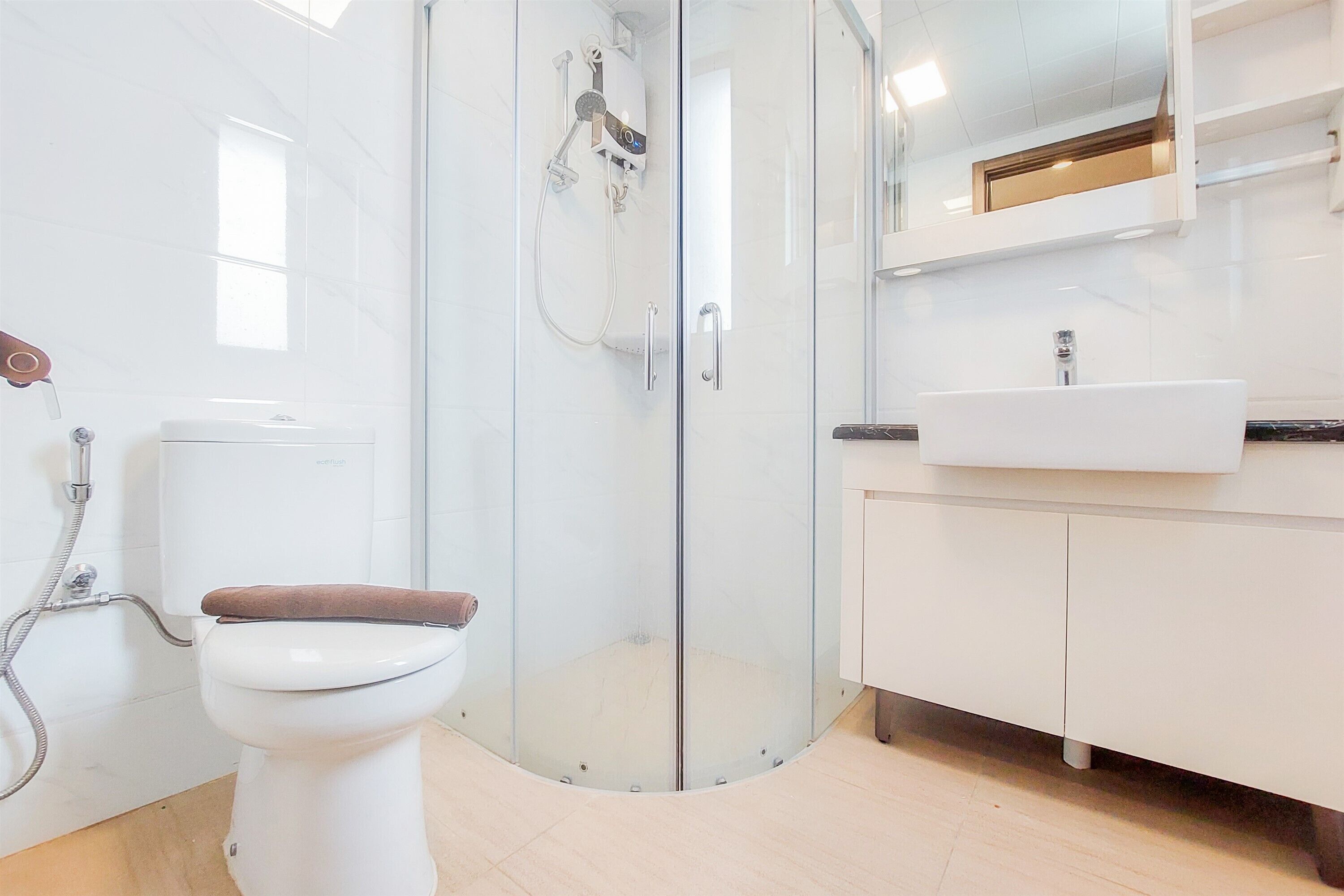 A modern bathroom with a glass-enclosed shower, a white toilet, and a sink with a mirror above it.