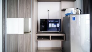 A modern kitchenette with a built-in TV displaying streaming services, a refrigerator, and a microwave. - Best Studio At Taman Melati Surabaya Apartment (Surabaya)
