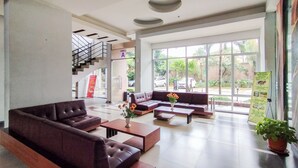 Eine geräumige Lobby mit Treppe, einer Couch, einem Couchtisch und einer Zimmerpflanze.