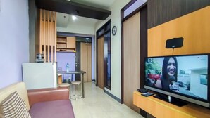 Ein kompakter Wohnbereich mit einer Couch, einem Fernseher und einer Küchenzeile.