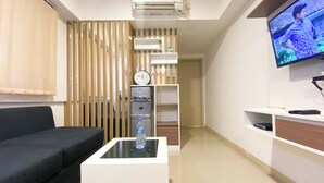 Un salon moderne équipé d’un téléviseur à écran plat, d’un distributeur d’eau et d’un canapé.