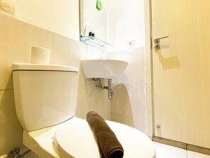 A bathroom with a toilet, a sink, and a glass shower enclosure. - Comfortable 2Br At 25Th Floor Meikarta Apartment (Cikarang)