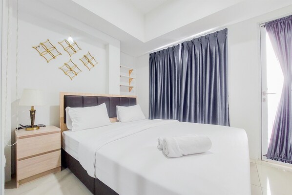 Relax in a stylish room with a large bed, geometric wall art, and a wooden nightstand.
