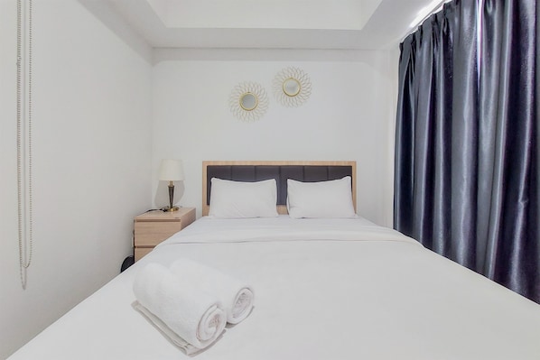 A neatly made bed with white linens and two rolled towels at the foot. - Cozy And Comfort Living 1Br Tamansari Bintaro Mansion Apartment (South Tangerang)