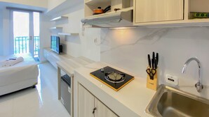 A modern kitchen with a built-in stove, a sink, and a countertop with kitchen utensils. - Cozy And Well Furnished Studio Tokyo Riverside Pik 2 Apartment (Jakarta)