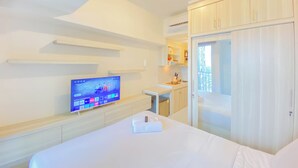A hotel room with a bed, a TV on the wall, a desk, and a wardrobe. - Cozy And Well Furnished Studio Tokyo Riverside Pik 2 Apartment (Jakarta)