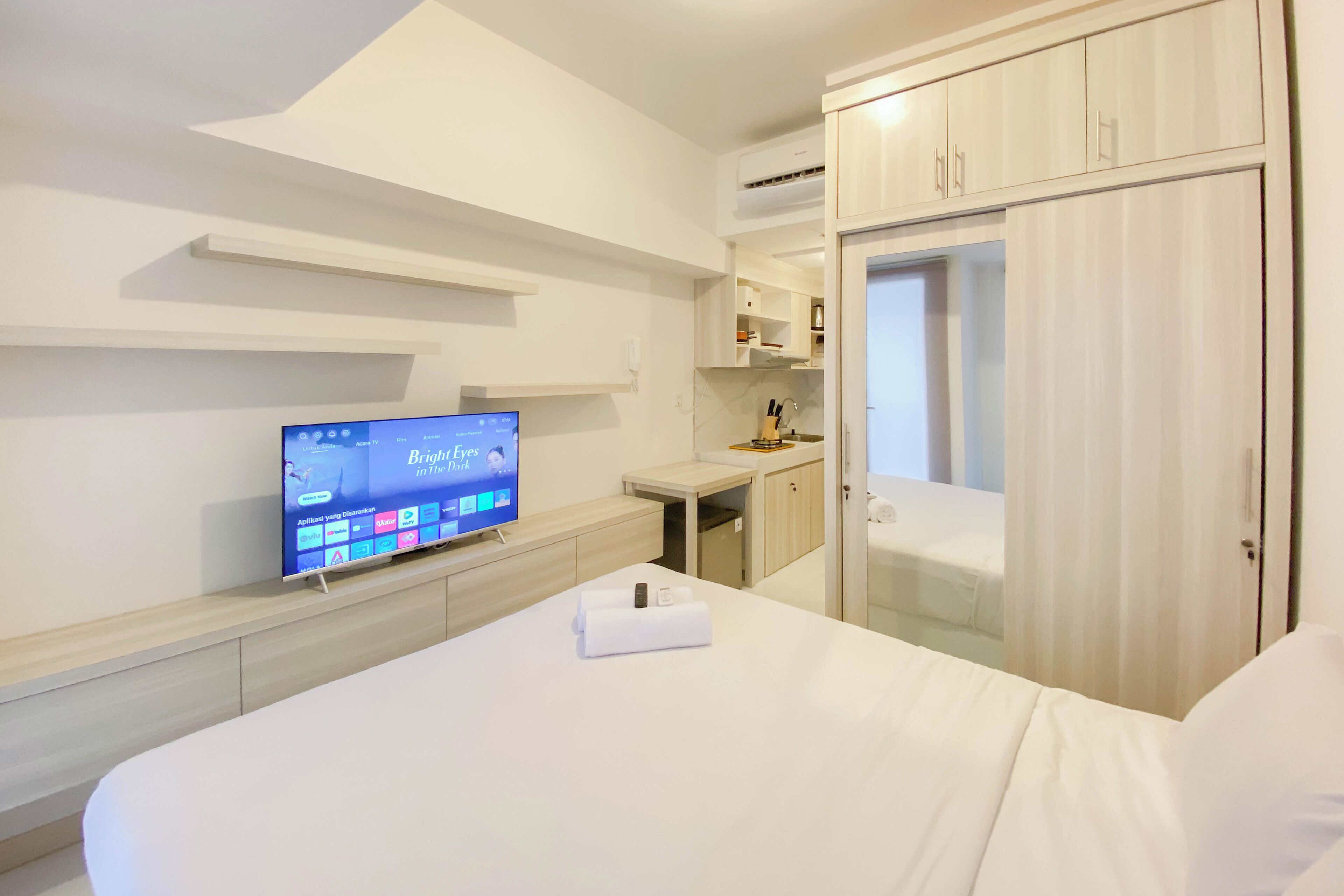 Habitación de hotel con cama, televisión sobre un mueble, escritorio y armario.