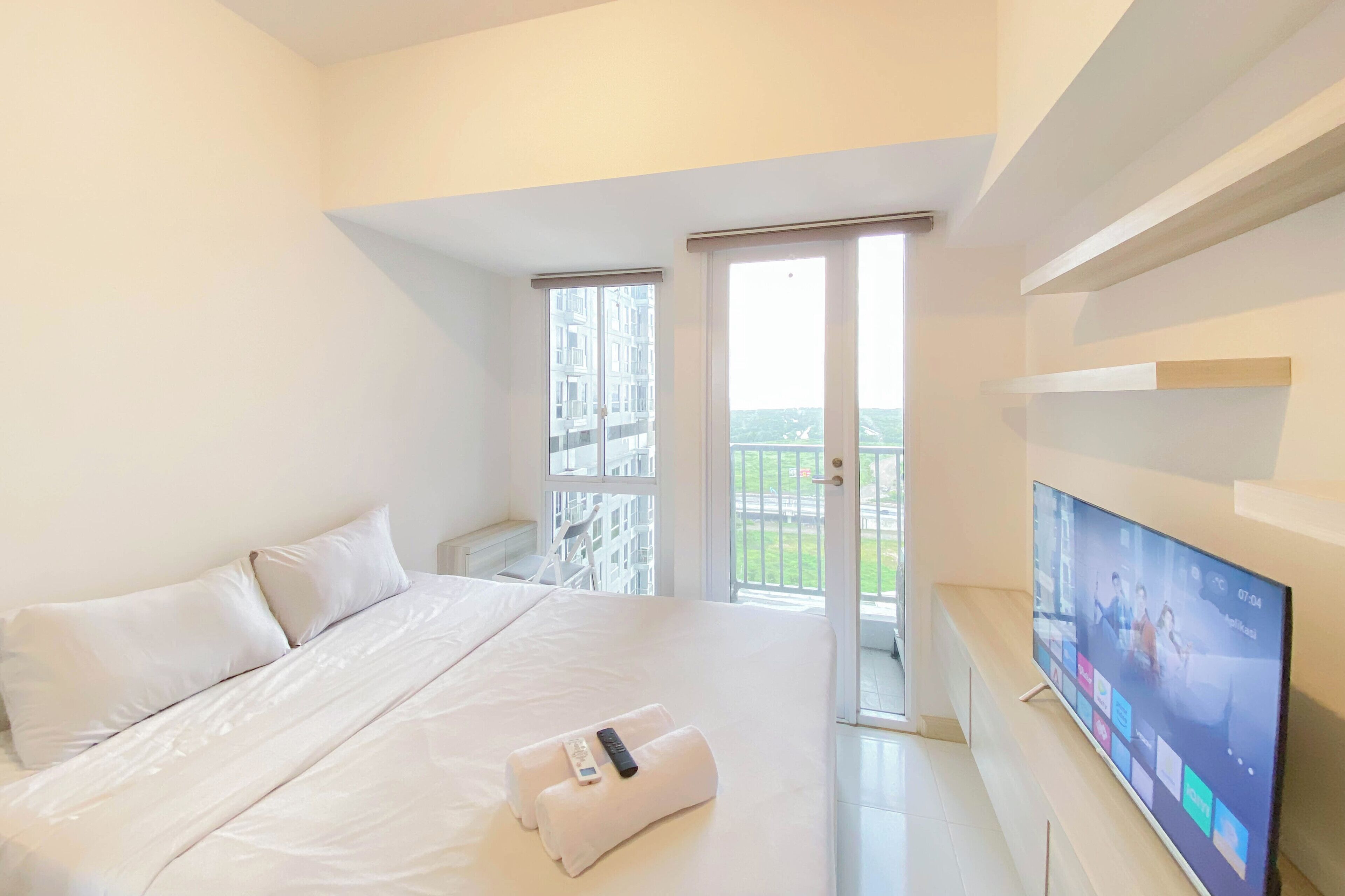 Une chambre d’hôtel avec un grand lit, un téléviseur fixé au mur et un balcon avec vue.