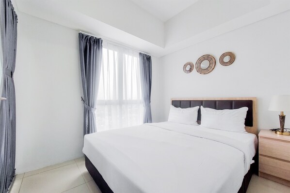 Relax in comfort with a large bed, a wall-mounted mirror, and a bedside table with a lamp.