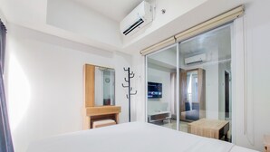 Camera d'albergo con un letto, una panca in legno, una TV e una porta scorrevole in vetro che dà su un balcone.