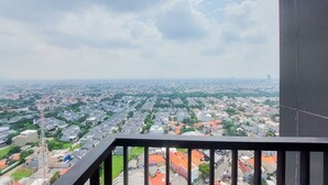 A balcony with a view of a residential area, including houses and a distant tower. - Comfort And Spacious 2Br At Tamansari Bintaro Mansion Apartment (South Tangerang)