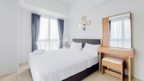 A neatly arranged hotel room with a large bed, a bedside table with a lamp, and a mirror. - Comfort And Spacious 2Br At Tamansari Bintaro Mansion Apartment (South Tangerang)