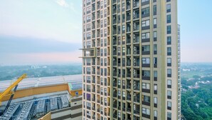 A high-rise building with multiple balconies and a construction crane in the foreground. - Restful And Homey 2Br At Transpark Cibubur Apartment (Bekasi)