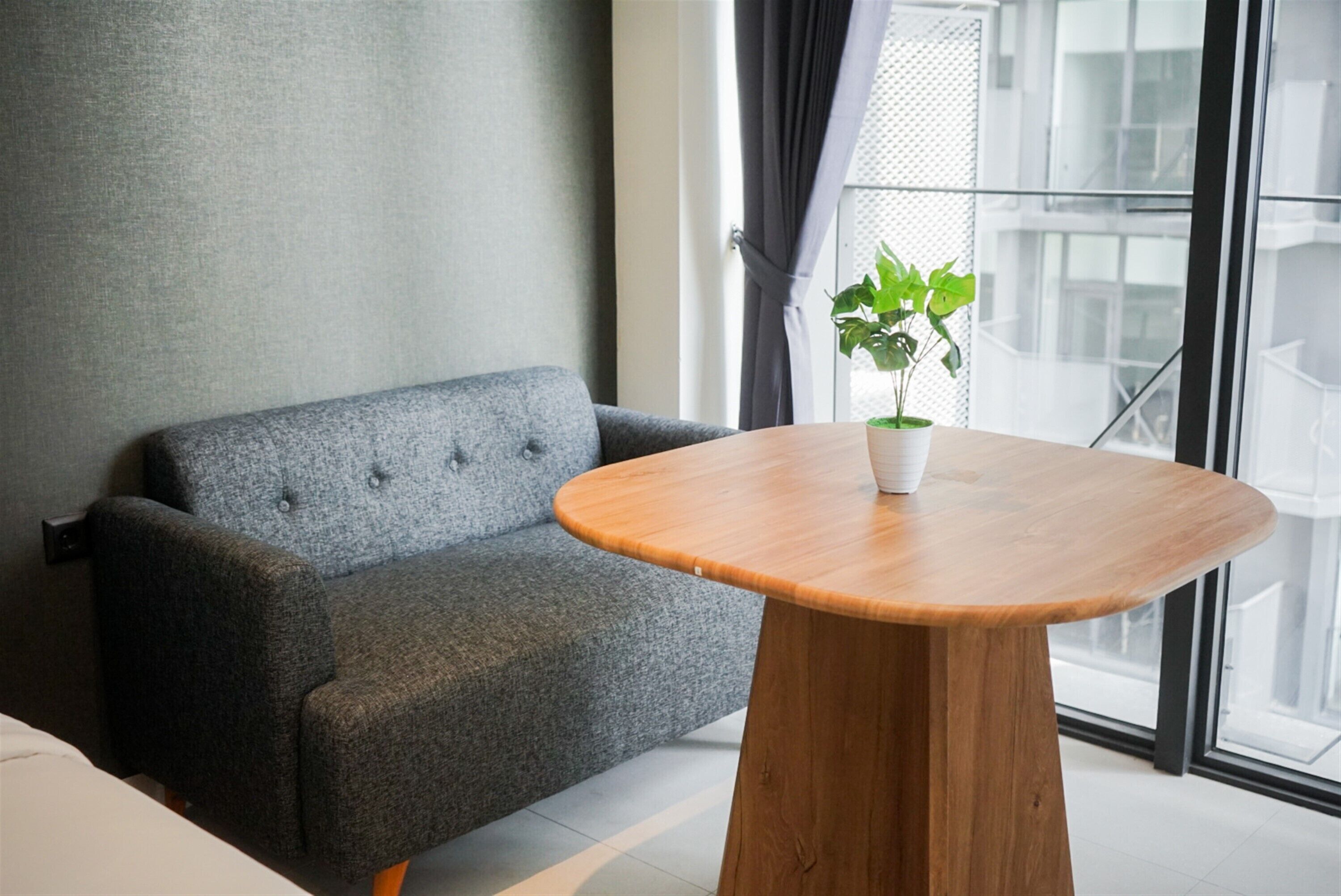 Una habitación moderna con un sofá gris, una mesa de madera y una planta en maceta.