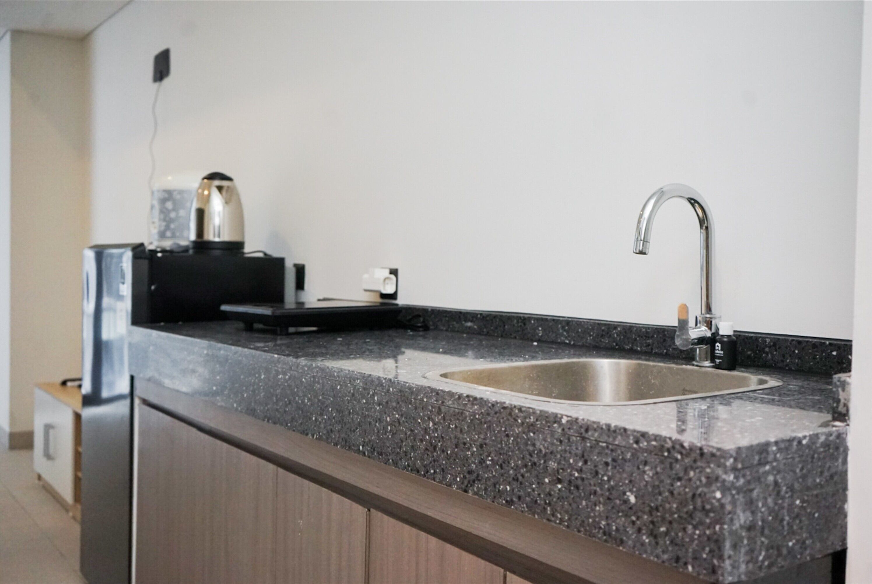 A kitchen with a granite countertop, stainless steel sink, and a coffee maker.