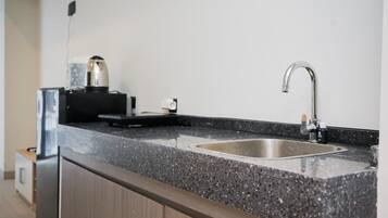 A kitchen with a granite countertop, stainless steel sink, and a coffee maker.