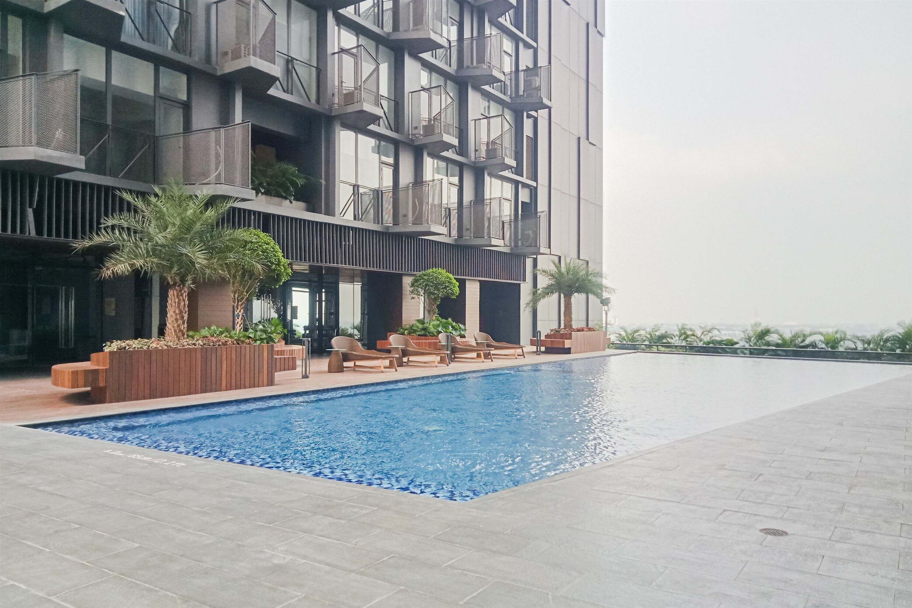 Un edificio moderno con piscina, mobiliario exterior y balcones.