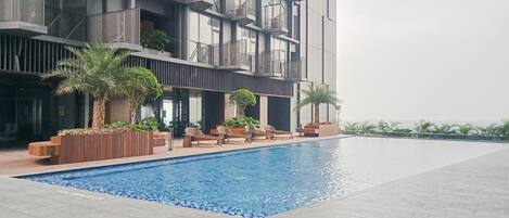 Un edificio moderno con piscina, mobiliario exterior y balcones.