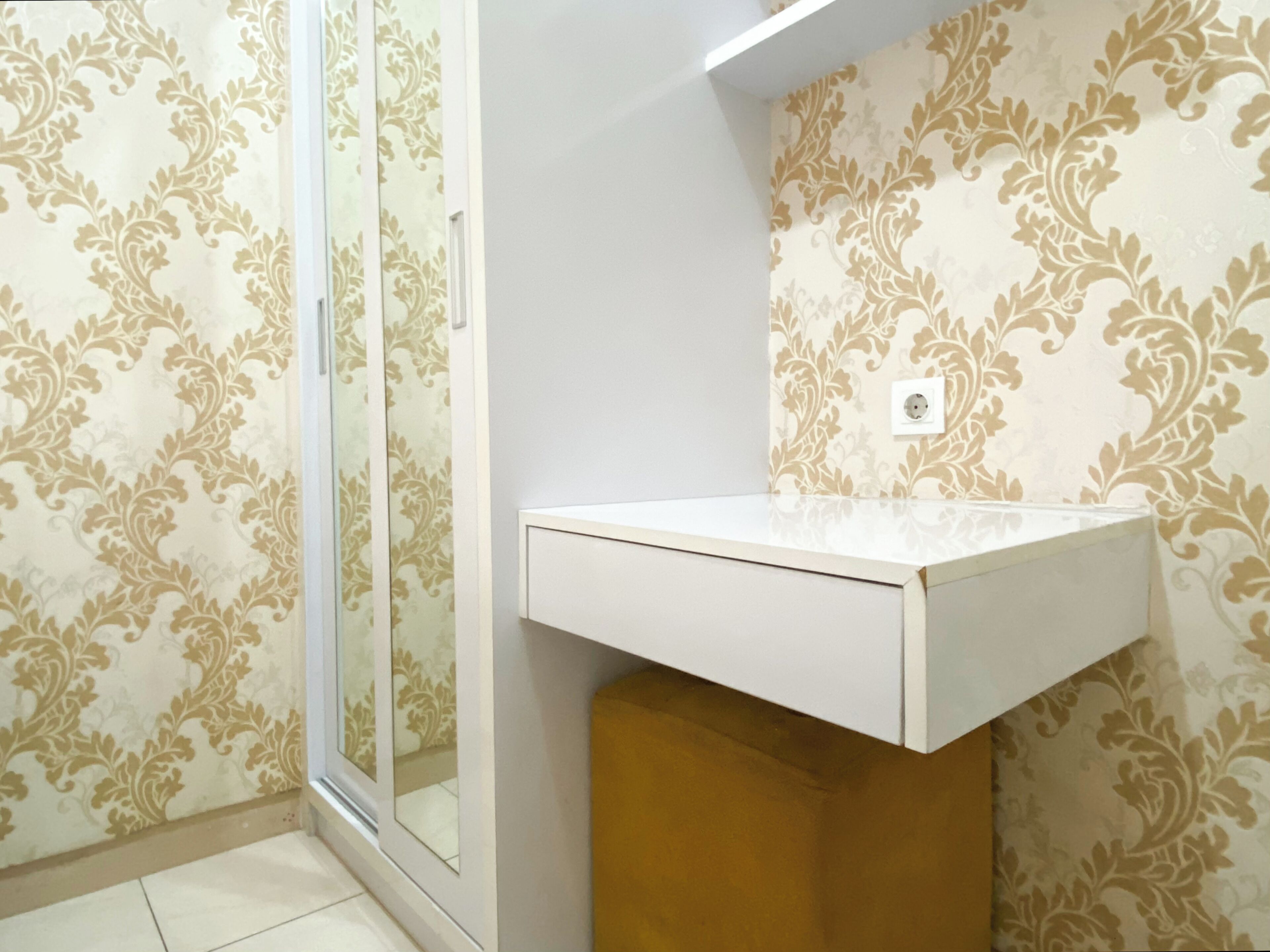 Bany amb un lavabo blanc, paper pintat i un compartiment de dutxa de vidre.
