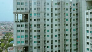 A high-rise residential building with multiple balconies, a view of the surrounding cityscape, and a clear sky. - Comfy And Homey 1Br At Sky Terrace Apartment (Jakarta)
