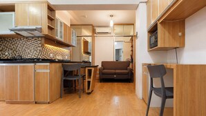 A compact kitchen with wooden cabinets, a tiled backsplash, and a central island with chairs. - Combined And Spacious 3Br At Green Pramuka City Apartment (Jakarta)